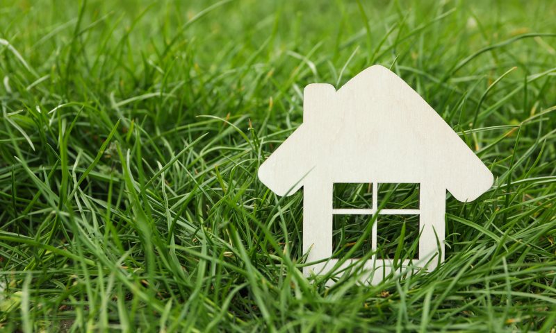 Small wooden house on green grass. Buying a property